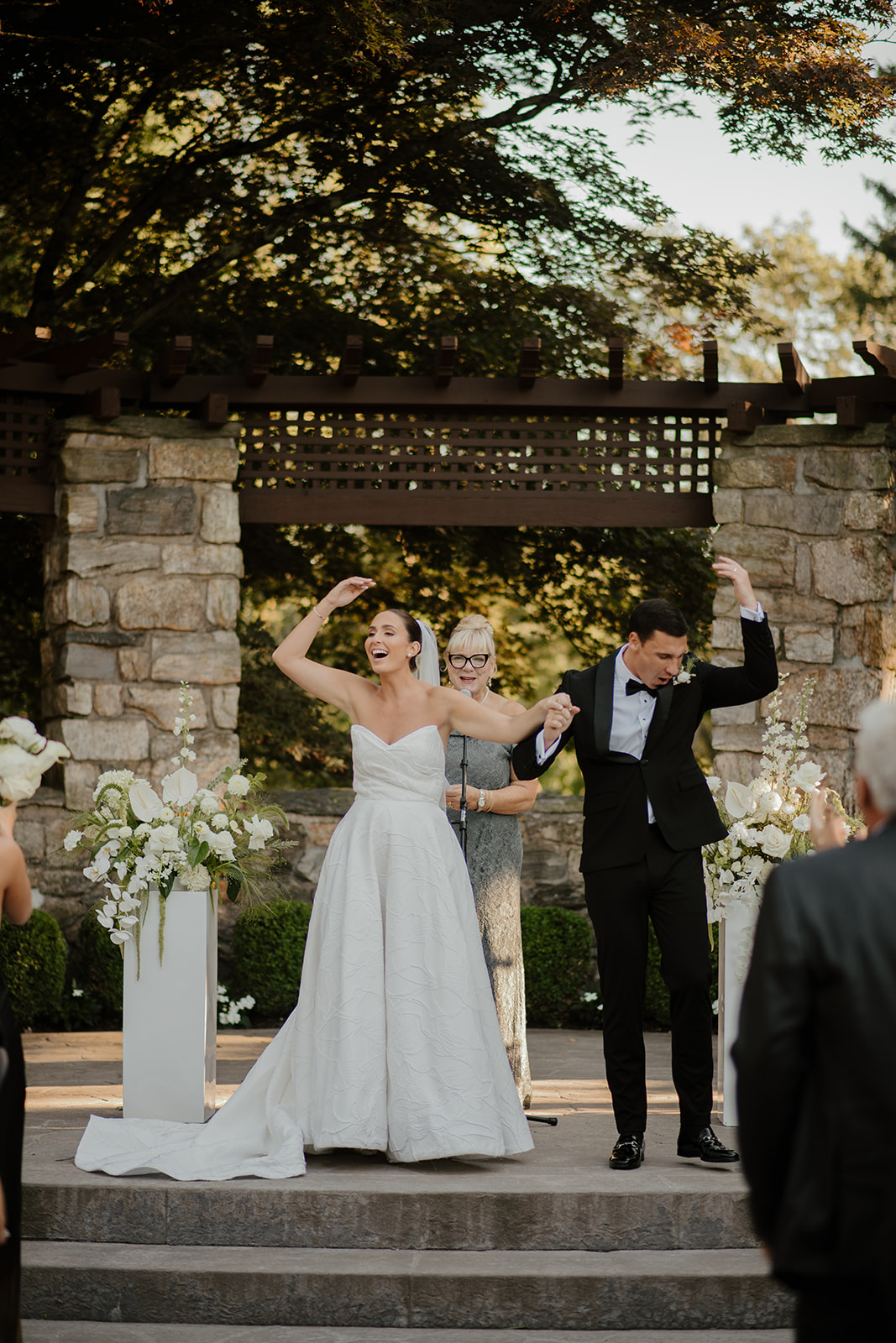 Newlyweds cheering with raised arms and holding hands at the altar immediately after being married.